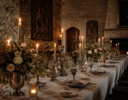 A candlelit long table prepared inside a historic European castle hall for an intimate private celebration.